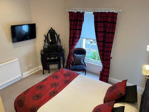 a bedroom with a bed and a tv and a window at The Original Rosslyn Inn in Roslin