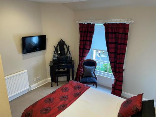 a bedroom with a bed and a tv and a window at The Original Rosslyn Inn in Roslin