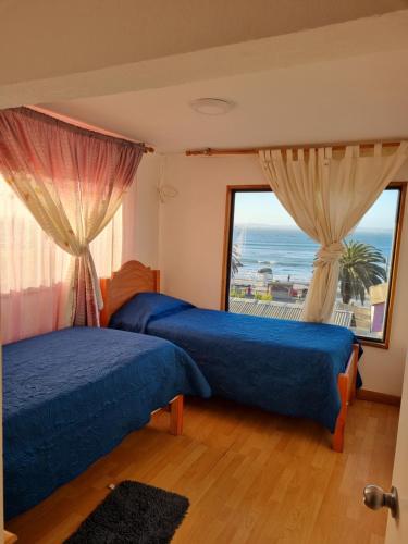 two beds in a room with a view of the ocean at Casas y cabañas Nofal in Los Vilos