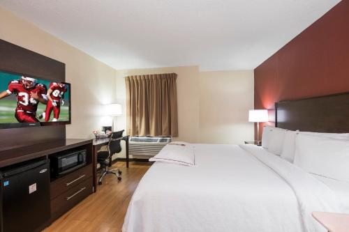 a hotel room with a bed and a flat screen tv at Red Roof Inn PLUS+ & Suites Opelika in Opelika