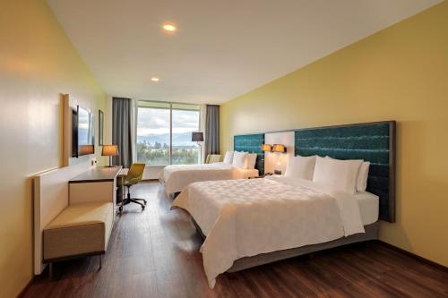 a hotel room with two beds and a desk at Holiday Inn - Quito Airport by IHG in Tababela