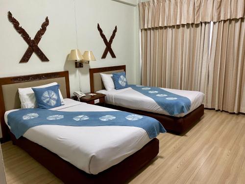 a bedroom with two beds with blue and white sheets at Maeyom Palace Hotel in Phrae