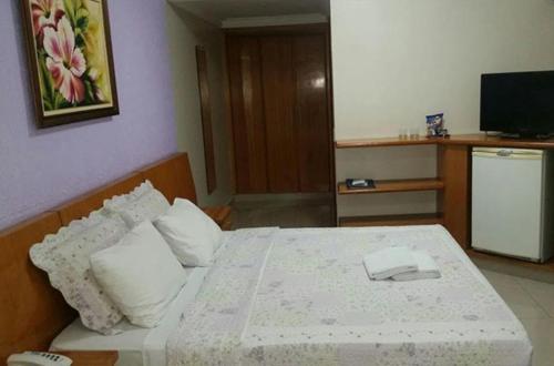 a bedroom with a white bed with a phone on it at Crystal Plaza Hotel Marista in Goiânia