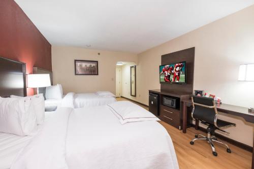 a hotel room with two beds and a desk at Red Roof Inn PLUS+ & Suites Opelika in Opelika