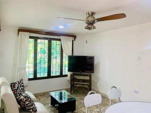 Una sala de estar con televisión, sofá y sillas. en Santa Marta Bello Horizonte - Cabañas Don Rafa, en Santa Marta