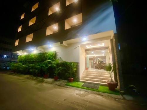 a building with stairs and potted plants at night at Hotel Vrindavan Palace in Indore