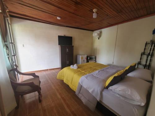 a bedroom with a large bed and a chair at CASA BLANCA HORTENCIA in Sucúa