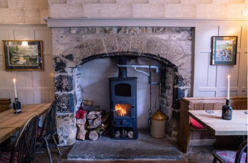 a stone fireplace with a stove in a room at Old Hall Hotel Hope in Hope