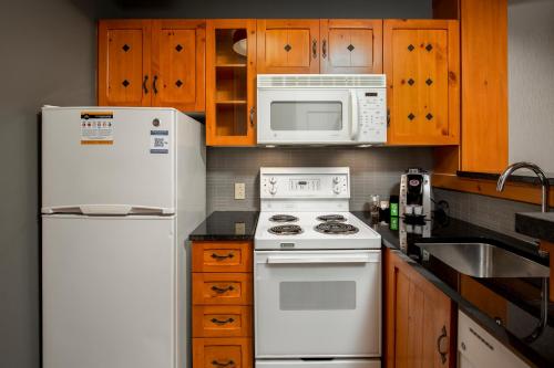 a kitchen with white appliances and wooden cabinets at Lodge de la Montagne in Mont-Tremblant