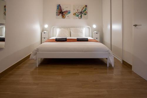 a bedroom with a white bed with butterflies on the wall at Spacious and Sunny Apartment - 10 min from the sea in Estoril