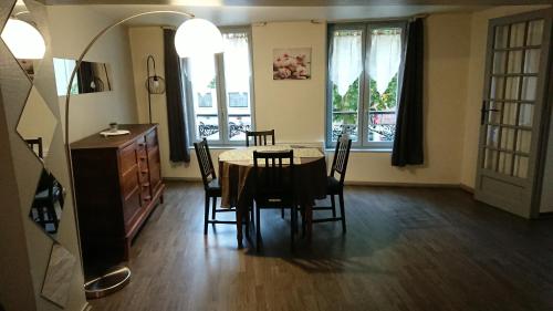 une salle à manger avec une table, des chaises et des fenêtres dans l'établissement Le Nid Rouennais, appartement 2 chambres, à Rouen