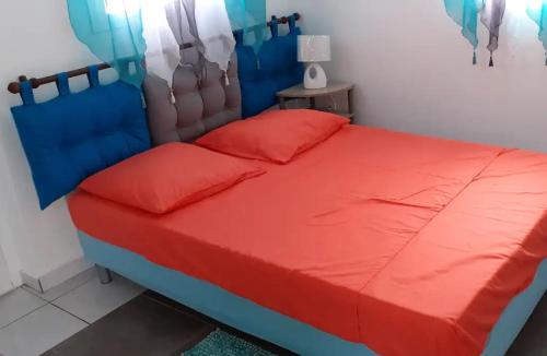 a bedroom with a bed with red and blue sheets at Maison charmante à Sainte-Anne in Sainte-Anne
