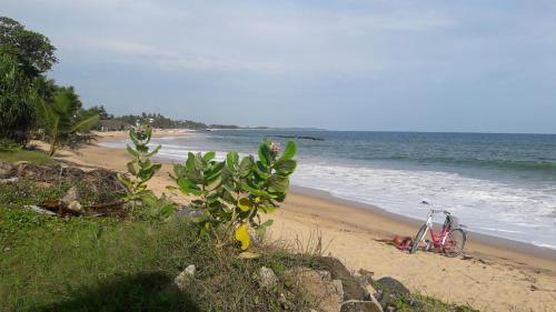 a bike parked on a beach next to the ocean at Gems Garden Guest House in Tangalle