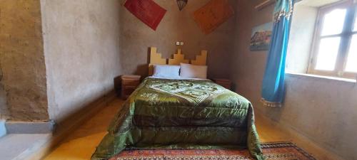 Un dormitorio con una cama en la esquina de una habitación. en Kasbah Dar Lgamra, en Merzouga