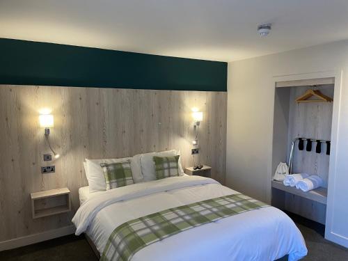 a bedroom with a large white bed with a green headboard at The White Horse in Cranswick