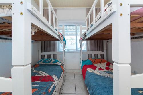 two beds in a room with two bunk beds at CASA COM PISCINA EM MORRINHOS - RUA HORTÊNCIA in Bombinhas
