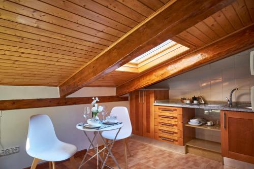 una cucina con soffitti in legno, tavolo e sedie di Apartamentos Madrid Atocha a Madrid