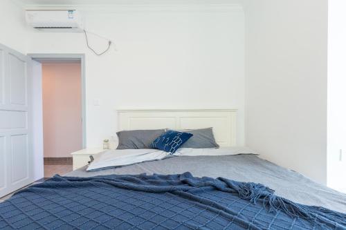 a bed with a blue blanket on top of it at Sanya Sun Seaview Apartment in Sanya