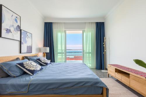a bedroom with a bed with a view of the ocean at Sanya Sun Seaview Apartment in Sanya