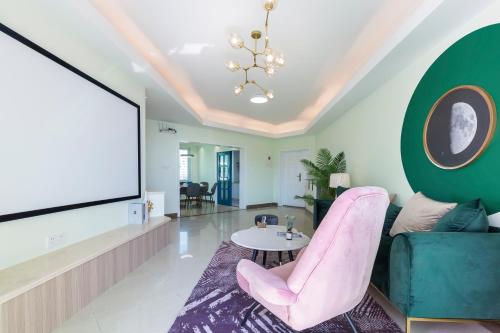 a living room with a flat screen tv and pink chairs at Sanya Sun Seaview Apartment in Sanya