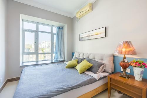 a bedroom with a bed and a window at Sanya Sun Seaview Apartment in Sanya