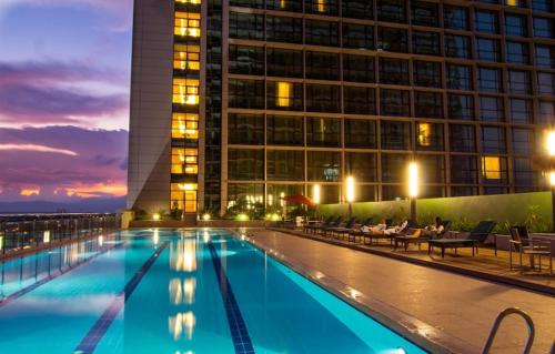 a swimming pool in front of a building at night at Imperial Hotel Kuching in Kuching