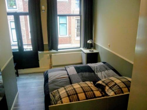 a bedroom with a bed and two windows at ALDO, not for parties, not a hotel, room with shared bathroom, no kitchen in Amsterdam