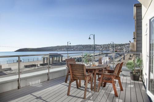 a table and chairs on a balcony with a view of the water at Atlantic View, Penzance in Penzance