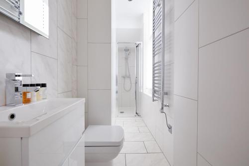 a white bathroom with a toilet and a shower at 2VH Virginia House, 31 Bloomsbury Way by City Living London in London