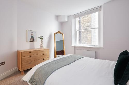 una camera con letto, cassettiera e finestra di 3VH Virginia House, 31 Bloomsbury Way by City Living London a Londra