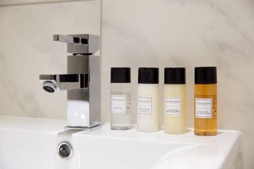 four bottles ofodorizers sitting on a counter next to a mixer at 3VH Virginia House, 31 Bloomsbury Way by City Living London in London