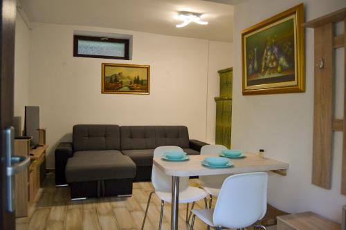a living room with a couch and a table and chairs at Irma- forrás Vendégházak in Verőce
