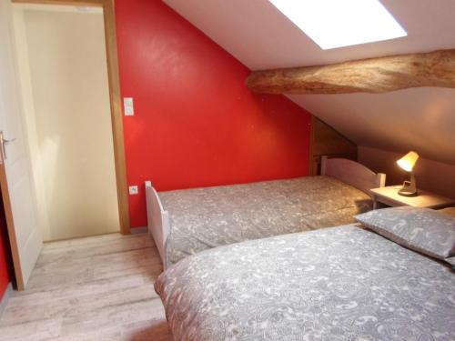 a bedroom with two beds and a red wall at Le fenil in Cornimont