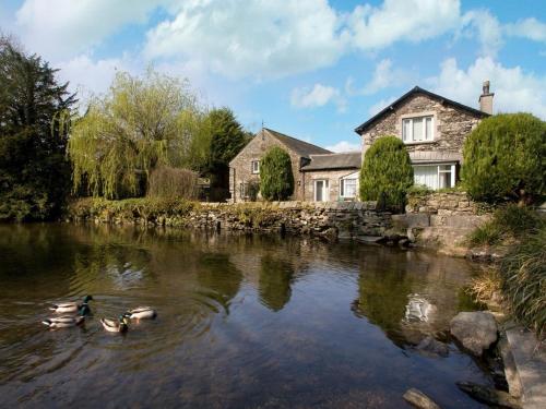 three ducks swimming in a river in front of a house at Little Wren Cartmel Couples Retreat in Cartmel