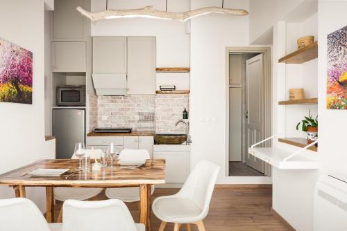 eine Küche und ein Esszimmer mit einem Holztisch und weißen Stühlen in der Unterkunft Sky Loft Corfu Old Town Apartments in Korfu-Stadt