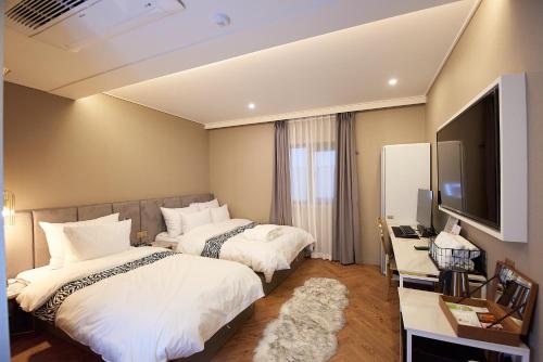 a hotel room with two beds and a television at Denbasta Hotel in Busan