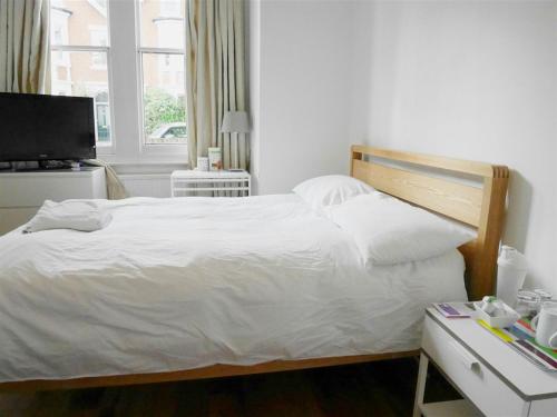 Schlafzimmer mit einem Bett und einem Schreibtisch mit einem TV in der Unterkunft Kew Studios and Rooms in Kew
