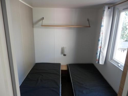 Cette petite chambre comprend un lit et une fenêtre. dans l'établissement Camping Les Sables du Midi, à Valras-Plage