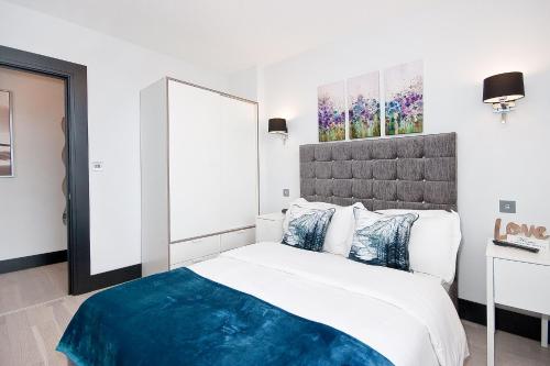 een witte slaapkamer met een groot bed met blauwe kussens bij Heinze Flat 402 - One bedroom fourth floor flat By City Living London in Londen