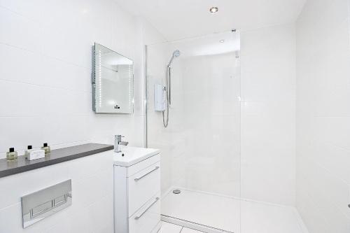 een witte badkamer met een wastafel en een douche bij Heinze Flat 402 - One bedroom fourth floor flat By City Living London in Londen