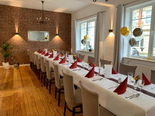 une rangée de tables dans une pièce avec des serviettes rouges dans l'établissement Hotel & Restaurant Wiggers, à Bad Oldesloe