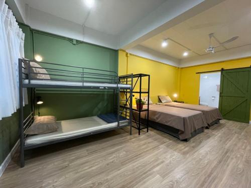 a bedroom with two bunk beds and a yellow wall at Grasshopper Bed and Cafe in Pak Kret