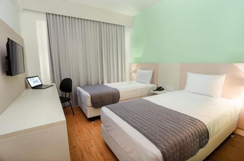 une chambre d'hôtel avec deux lits et une télévision dans l'établissement Go Inn Goiana by Atlantica Hotels, à Goiana
