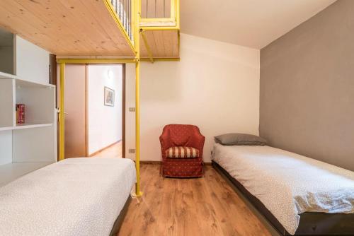 a bedroom with two beds and a chair at Agriturismo Al Gallo Nero Giallo in Tenno