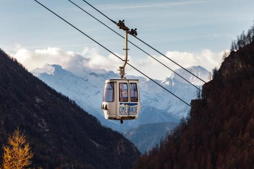 a cable car is flying through the mountains at HelloChalet - Maison Rue de la Neige - Family Ski Holiday walking distance skirun and gondola in Valtournenche