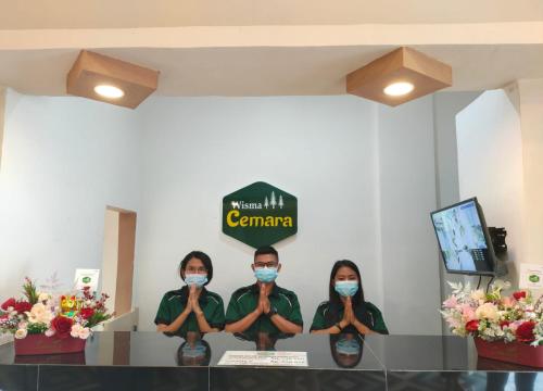 un gruppo di tre donne che indossano maschere in una stanza di Wisma Cemara Dumai a Dumai