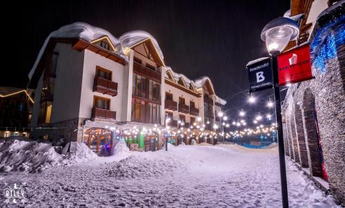 a snow covered street in front of a building with lights at GVC New Gudauri Alpic Mountain view in Gudauri