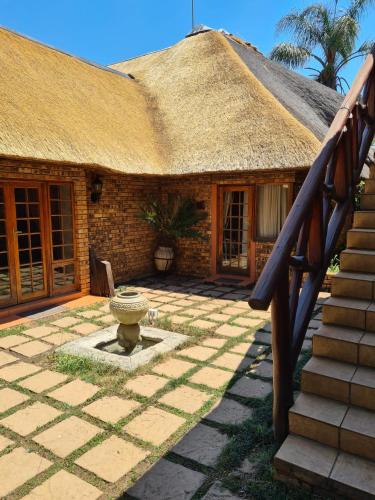 a house with a thatched roof and a stone patio at Khaya Africa Guesthouse in Midrand