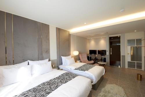 a hotel room with two beds and a chair at Denbasta Hotel in Busan