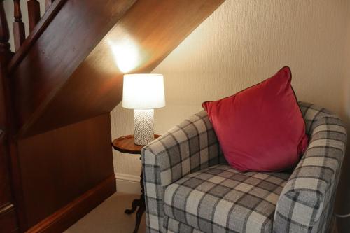 a couch with a red pillow sitting next to a lamp at The Horseshoe Country Inn in Pickering